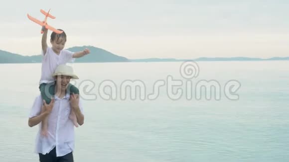 快乐的亚洲家庭在度假时父子俩直起胳膊在海滩上搭飞机玩得开心快乐视频的预览图