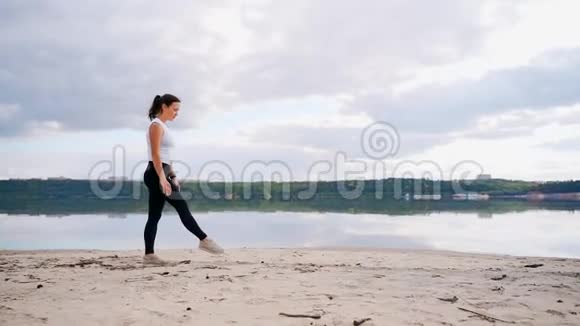 河沙滩上的一个年轻女孩练习瑜伽海滩上的女孩站在桥上的姿势视频的预览图