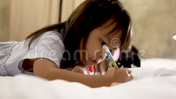 可爱的小女孩在家里的床上做作业视频的预览图