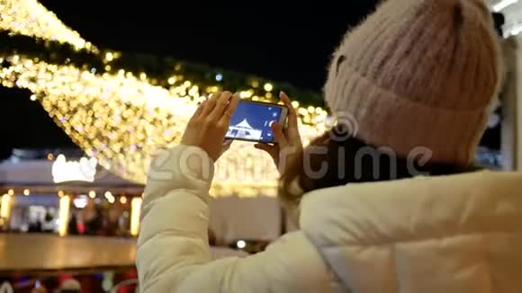 穿夹克的年轻女子在户外给圣诞树打电话视频的预览图