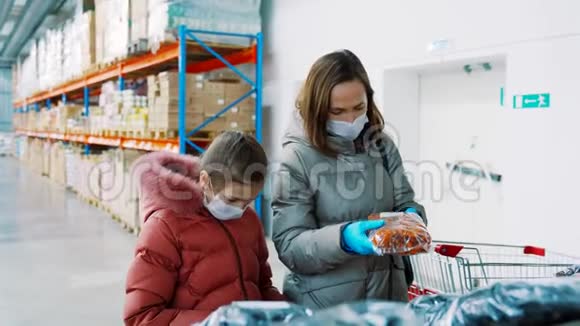 一个女人带着女儿穿着冬天的衣服在商店里戴着医用口罩买了杏干干果视频的预览图