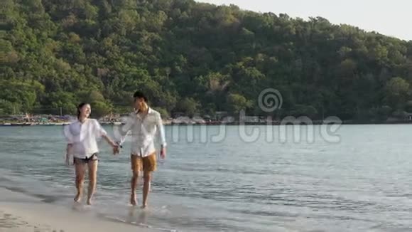 快乐的亚洲情侣在夏天和浪漫的情侣一起在海滩上散步手牵手休闲视频的预览图