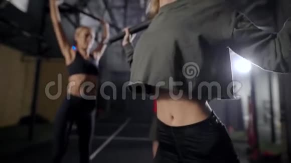 男教练在健身房里控制着两个性感的女人的锻炼女士们正在举起棒子和蹲下视频的预览图