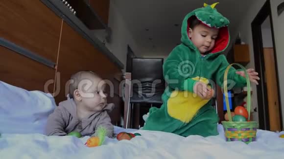 可爱的兄弟姐妹穿着兔子和恐龙服装玩复活节彩蛋视频的预览图