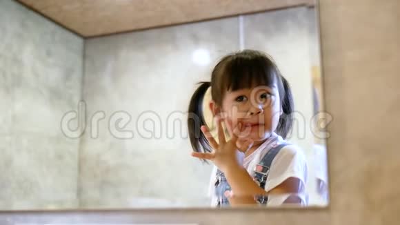 可爱的小女孩化妆在房间里的镜子里玩得很开心视频的预览图