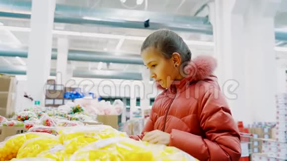小女孩穿着超市里的冬季夹克选择黄色的窗帘视频的预览图