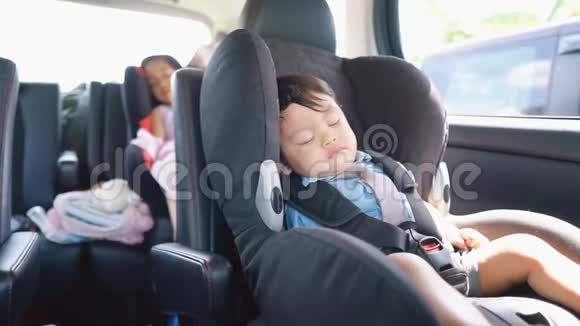 一个可爱的亚洲男孩睡在他的汽车座椅上以及他的兄弟姐妹的视频视频的预览图
