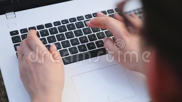 女性手上的顶部视图在笔记本键盘上键入一些文本在户外工作的女人女孩上网视频的预览图