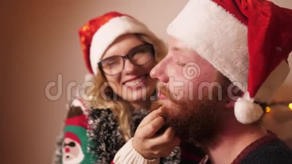 穿着毛衣的女孩为圣诞节抚摸男友的胡须微笑着视频的预览图