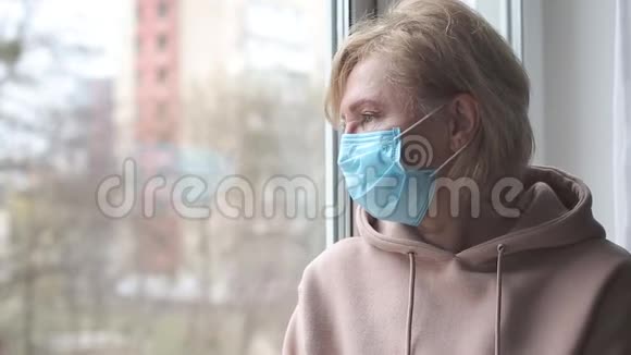 窗户附近戴着医疗面具的悲伤女人视频的预览图