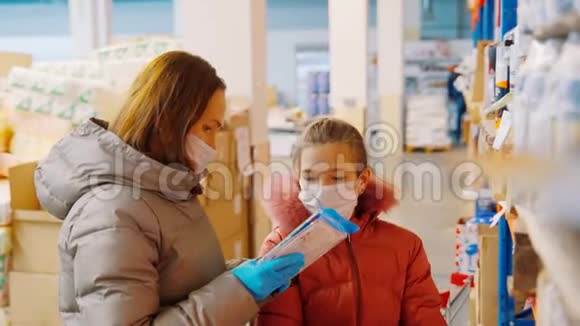 妈妈和女儿在批发仓库选择货物带着女儿戴着医用口罩的女人视频的预览图