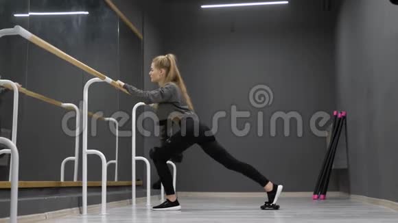 金发女人手里拿着哑铃做体育锻炼在体操馆里活动腿视频的预览图