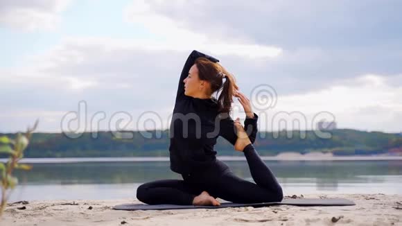 河沙滩上的一个年轻女孩练习瑜伽伸展身体视频的预览图