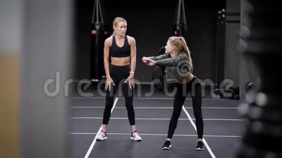 两个性感的健身模特女孩在健身房锻炼伸展肌肉保持身体健康视频的预览图