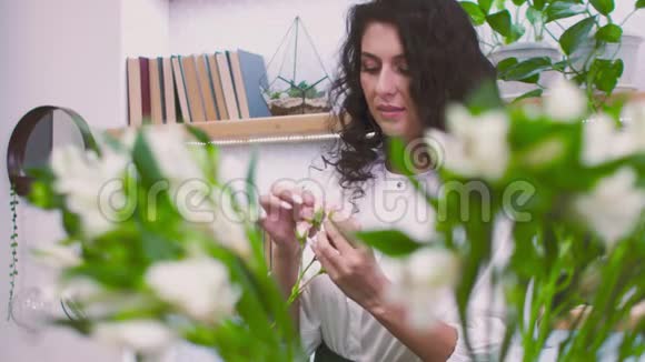 年轻迷人的女花店商人在他的花店里做一束花出售人民视频的预览图