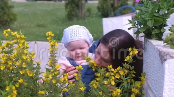 妈妈和女儿宝宝在公园里散步抱着她看着花视频的预览图