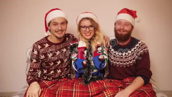 三个穿着圣诞服装戴着帽子微笑的青少年在音乐中缓慢地跳舞视频的预览图