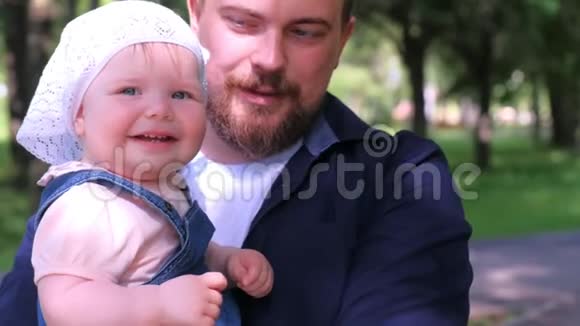 年轻的爸爸抱着女儿在城市公园家庭肖像看着相机视频的预览图