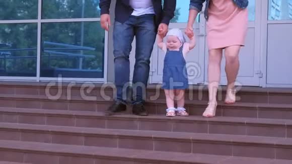 小女孩学着走牵着父母的手走下台阶视频的预览图