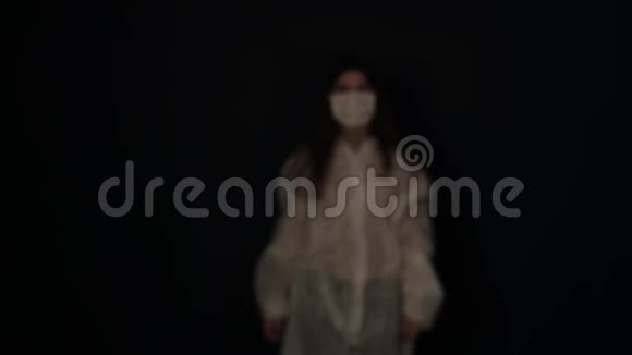 年轻可爱的白种人女孩从黑暗中出现戴上了医疗面具冠状病毒COID19视频的预览图