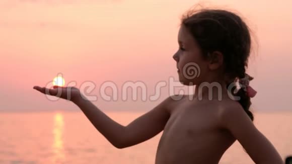可爱的女孩手捧太阳在海边视频的预览图