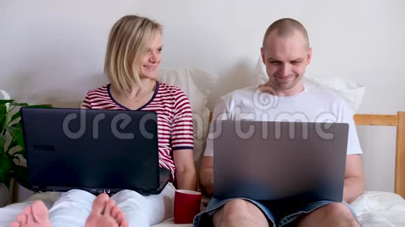 4k年轻的一家人在电脑旁的床上远程工作隔离夫妇冠状病毒呆在家里安全视频的预览图