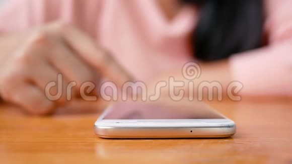 在度假的日子里一位使用智能手机坐在客厅里的亚洲年轻女性被关闭了视频的预览图