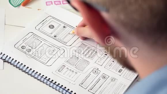 UX设计师在笔记本上绘制了一款新应用的草图原型视频的预览图