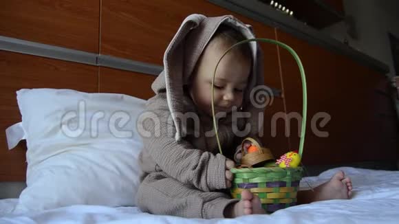 可爱的小男孩伸手去拿复活节彩蛋的肖像复活节兔蛋狩猎概念视频的预览图