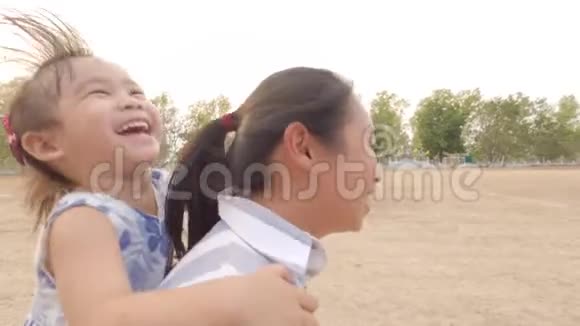 快乐的小女孩坐在妈妈背上在公园里跑步幸福家庭和童年的概念视频的预览图