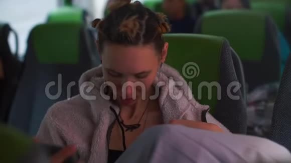 一个女人坐公共汽车双手调整耳机视频的预览图