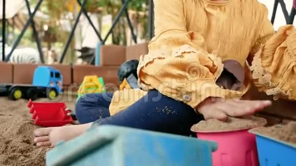 快乐的小女孩在阳光明媚的夏天玩塑料玩具坐在沙箱里视频的预览图