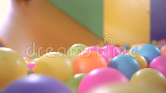 可爱的小女孩在塑料干池里玩滑梯里面有五颜六色的球在孩子们的操场室内视频的预览图