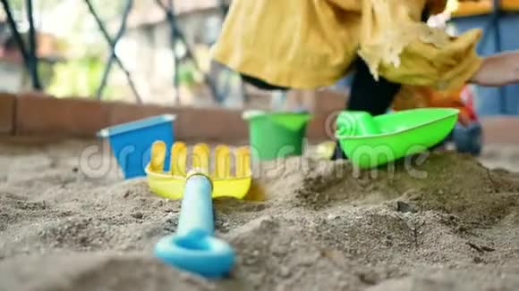 快乐的小女孩在阳光明媚的夏天玩塑料玩具坐在沙箱里视频的预览图