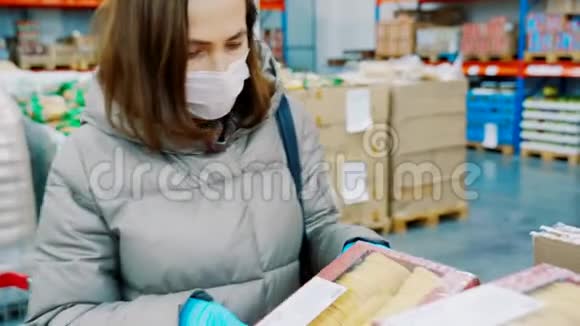 一个女人正在一个批发杂货店买杂货穿冬天衣服的女人和商店里的医疗面具视频的预览图