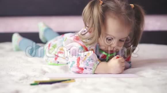 一个穿着晨衣的小女孩坐在沙发上咬着嘴唇的特写镜头有两个辫子的可爱宝宝视频的预览图
