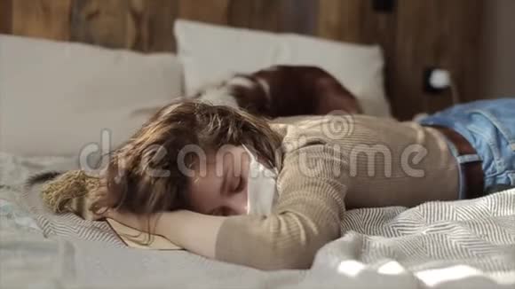 一个年轻漂亮的女孩在家里戴着防护面具在检疫期间和她的狗玩冠状病毒COVID19视频的预览图