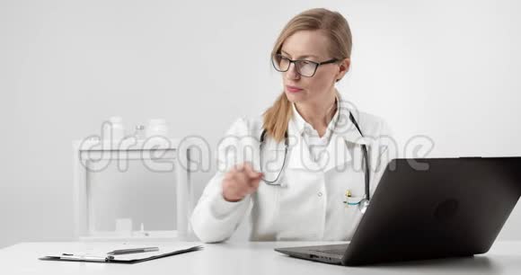 坐在餐桌上使用笔记本电脑的医疗专家视频的预览图