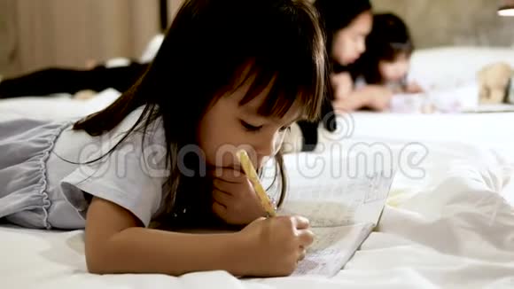 可爱的小女孩在家里的床上做作业视频的预览图