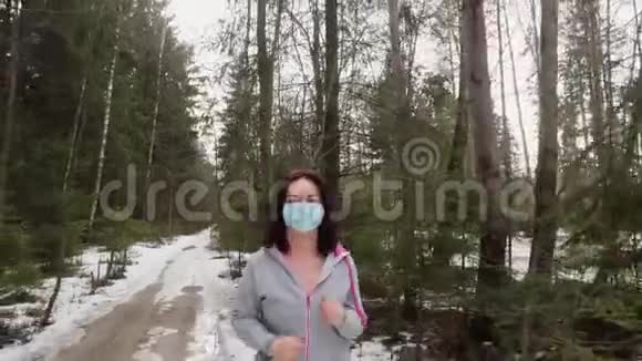 女人在森林里奔跑脸上戴着医用一次性口罩预防病毒视频的预览图