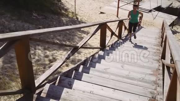 一个女孩沿着一个从悬崖上升起的木制楼梯奔跑视频的预览图