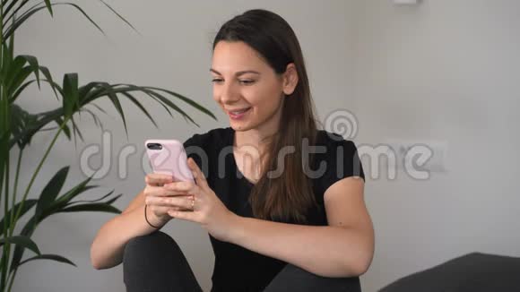 年轻的女人在家里用手机快乐的白种人女孩影响者视频的预览图