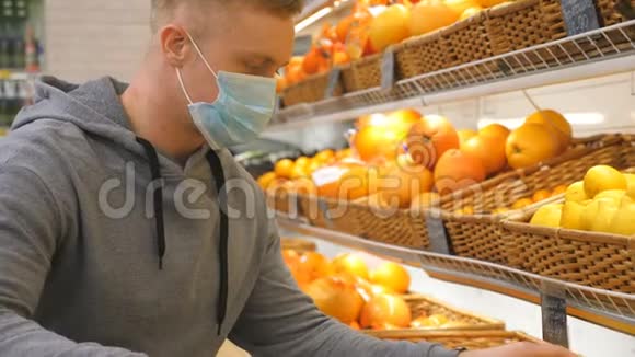 带医用口罩的男士在店里挑选柠檬男人在超市里选择水果购买农产品视频的预览图