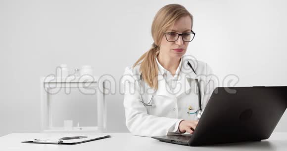 穿着医用制服的女医生在笔记本电脑上工作视频的预览图