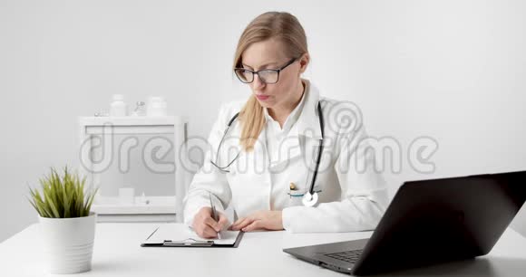 成熟的医生使用笔记本电脑在办公室写论文视频的预览图