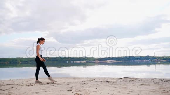 河沙滩上的一个年轻女孩练习瑜伽海滩上的女孩站在桥上的姿势视频的预览图