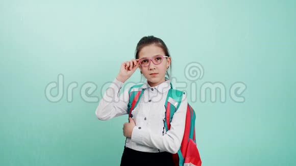 一个年轻的女学生一只手拿着眼镜架一个戴着蓝色背景眼镜的女学生的肖像A视频的预览图