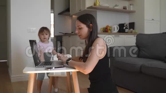 在家工作的年轻女子带着小孩妈妈家庭办公室快乐视频的预览图