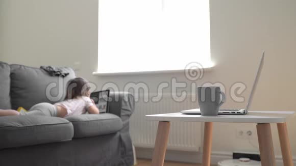 客厅里有婴儿在沙发上看动画片父母在家里办公场所视频的预览图
