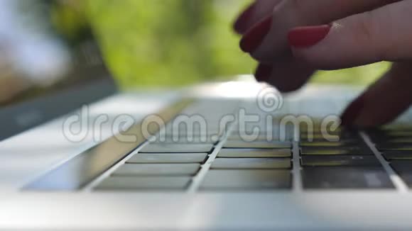 用红色指甲在笔记本电脑键盘上输入一些文字的女性手指的详细视图女商人用笔记本视频的预览图